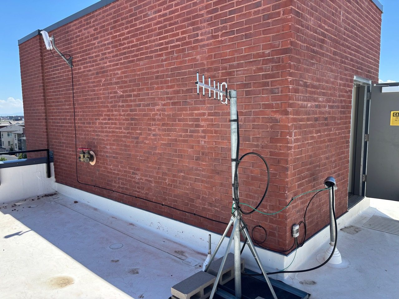 Rooftop antenna mast and cabling against a brick structure